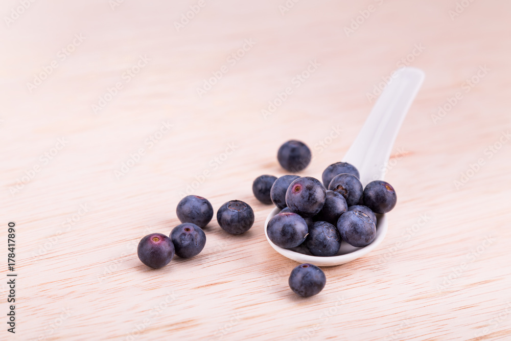 Organic blueberries scooped in spoon on wooden surface Organic blueberries scooped in spoon on wooden surface
