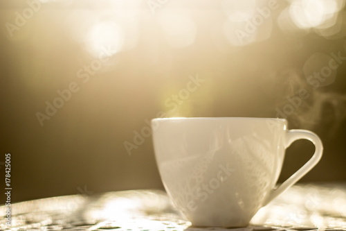 A white of coffee on white table in the garden, coffee break in the morning with light bokeh , relaxing and refreshing concepts.