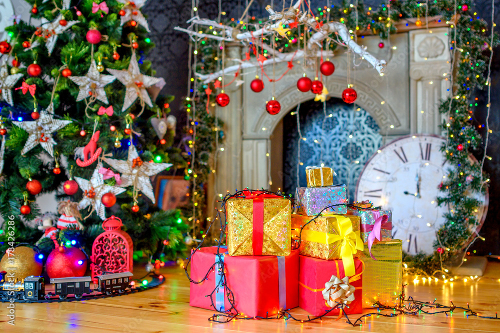 Christmas background, a lot of boxes with gifts lies near the festive Christmas tree, in the background bright lights.