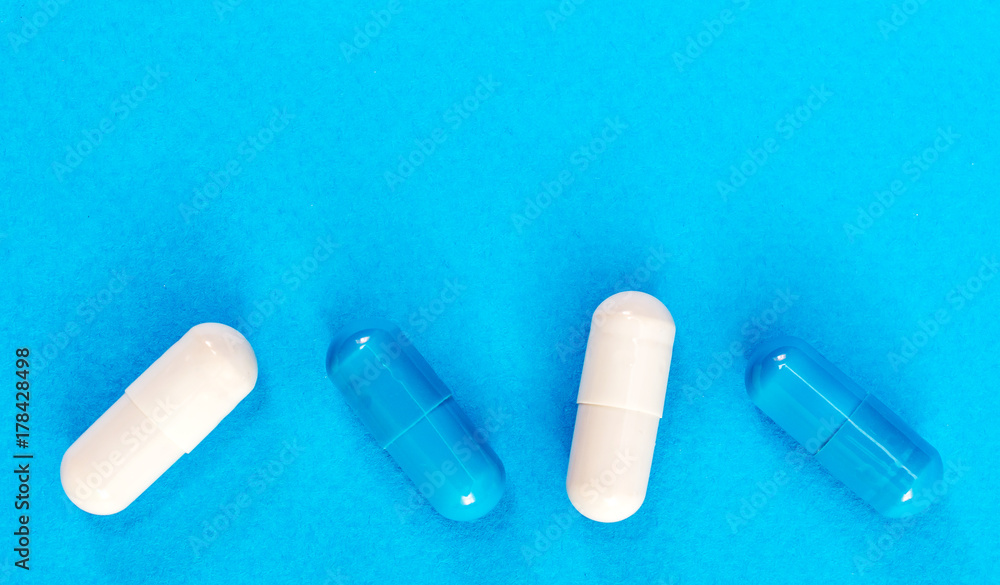 Row of medical capsules on a blue background. Top view. Medical background. Row of medical capsules on a blue background. Top view. Medical background.