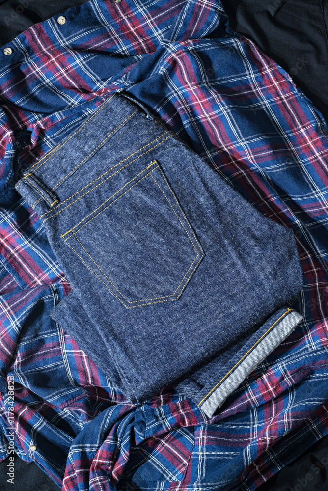 Blue Jeans Denim, 100% Cotton Unsanforized Denim Red Selvage Jeans on Plaid Shirt background, selective focus (detailed close-up shot) Blue Jeans Denim, 100% Cotton Unsanforized Denim Red Selvage Jeans on Plaid Shirt background, selective focus (detailed close-up shot)