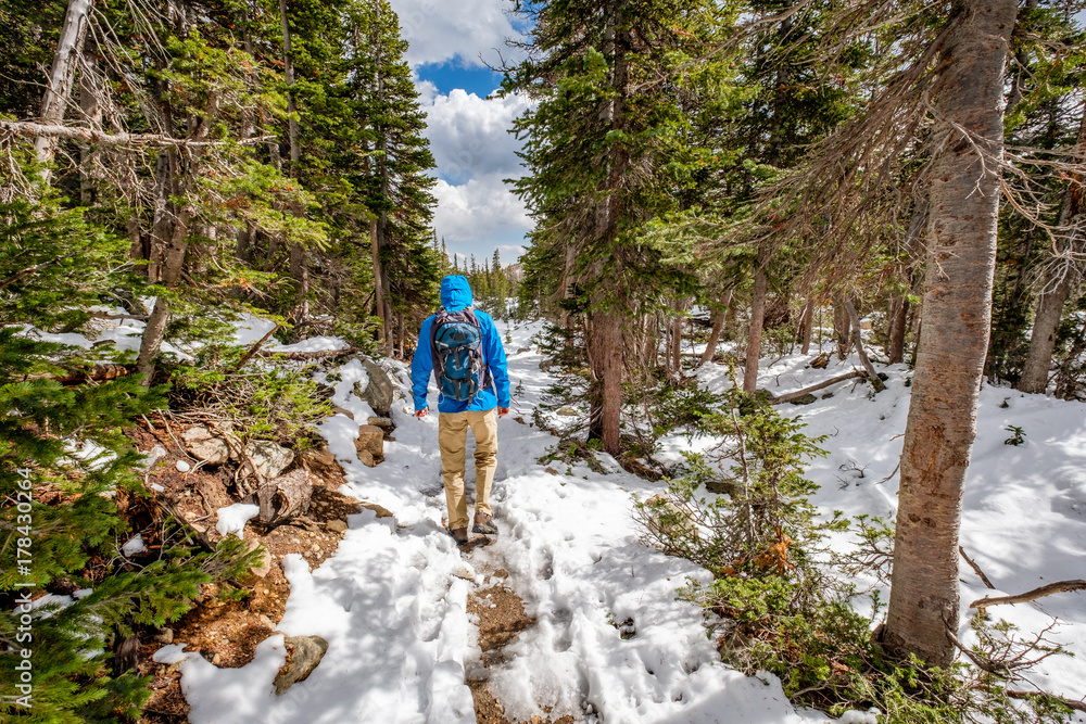 Tourist with backpack hiking on snowy trail
