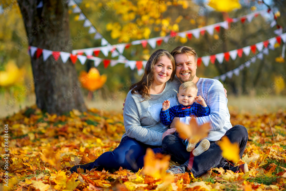 happy family walking in beautiful autumn park, sitting on grass and playing. happy family walking in beautiful autumn park, sitting on grass and playing.