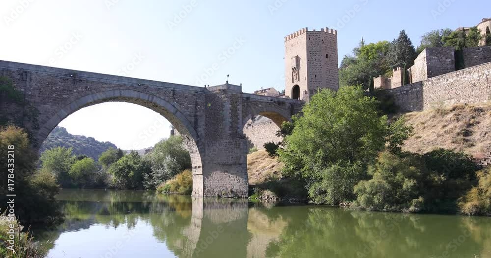4k video. Tilting moving shot from down green water river Tagus, Tajo in Spanish, to up Alcantara arch bridge and door, landmark and monument from ancient Roman age, in Toledo city, Spain, Europe
4k video. Tilting moving shot from down green water river Tagus, Tajo in Spanish, to up Alcantara arch bridge and door, landmark and monument from ancient Roman age, in Toledo city, Spain, Europe