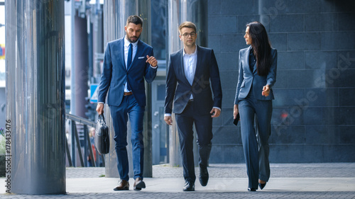 Tableau sur Toile Male and Female Business People Walk and Discuss Business