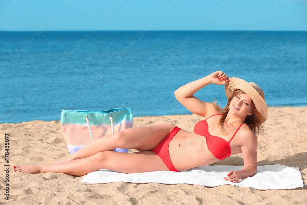 Young woman with nice body sunbathing on sea beach