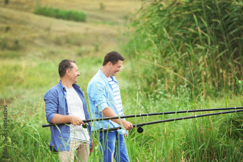 Men fishing from shore on river Men fishing from shore on river