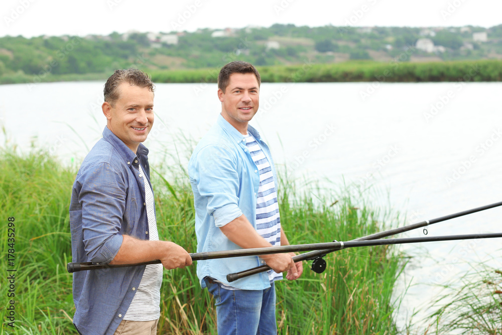 Men fishing from shore on river Men fishing from shore on river