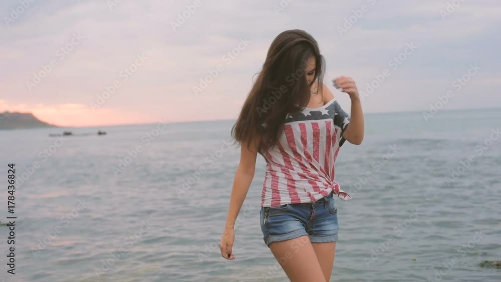 young beautiful female on beach during sunrise with USA flag. 4th july concept