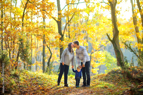 happy family walking in beautiful autumn park at sunset. © Tortuga