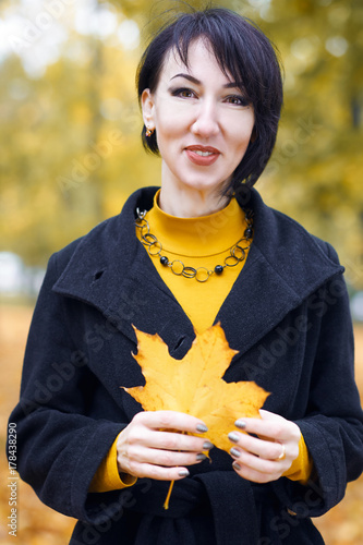 beautiful girl portrait with yellow leaf in hand  autumn city park on background  fall season