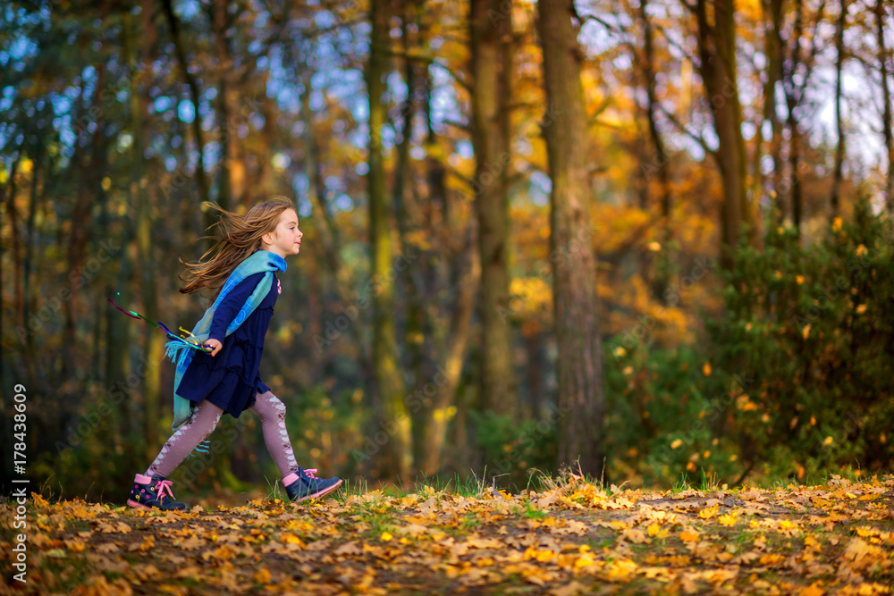beautiful little girl is playing and running in the autumn park. beautiful little girl is playing and running in the autumn park.