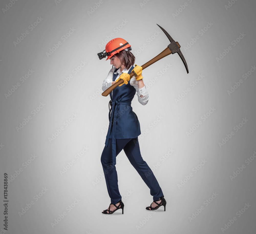 Naklejka premium Business woman with a pick on gray background. Studio shoot. Mining cryptocurrency concept