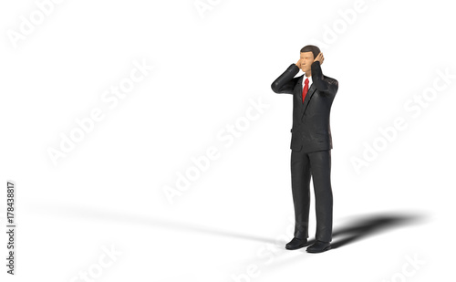 toy miniature businessman figure covering his ears in front of an empty space, concept isolated with shadow on white background