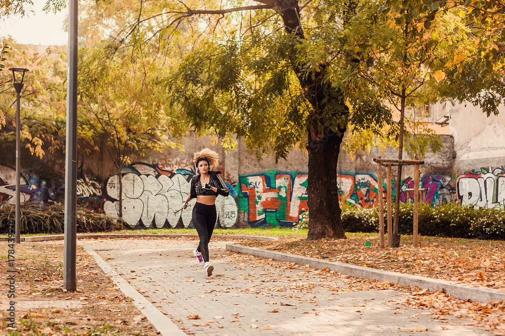 Fototapeta premium Beautiful jogger portrait running in urban autumnal park