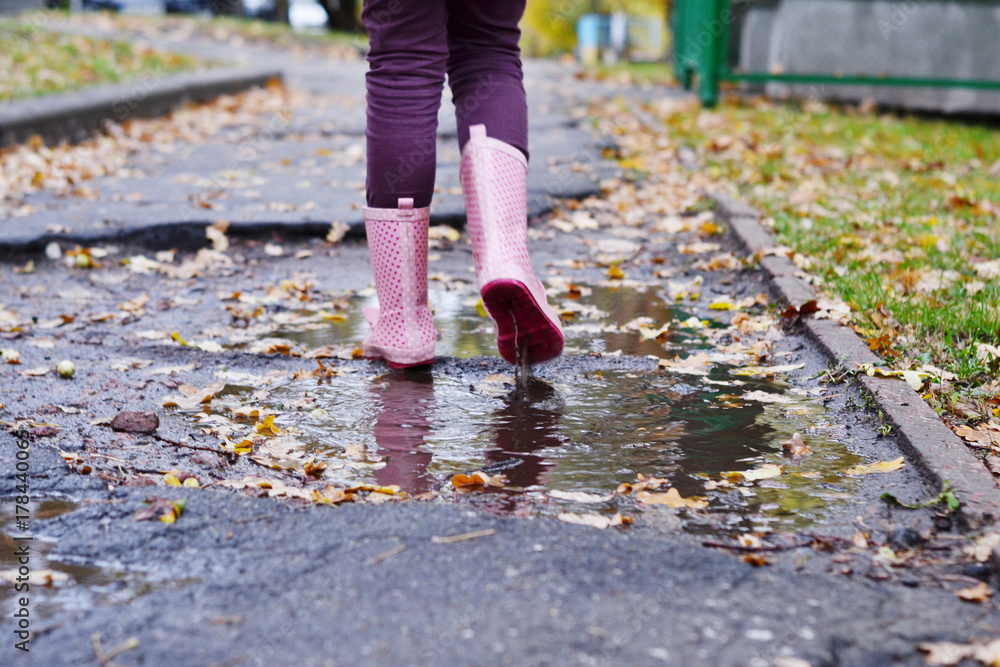 A girl in rubber boots wanders through the puddle A girl in rubber boots wanders through the puddle