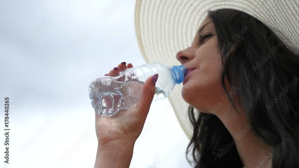Beautiful woman drinks water from a bottle on nature Beautiful woman drinks water from a bottle on nature