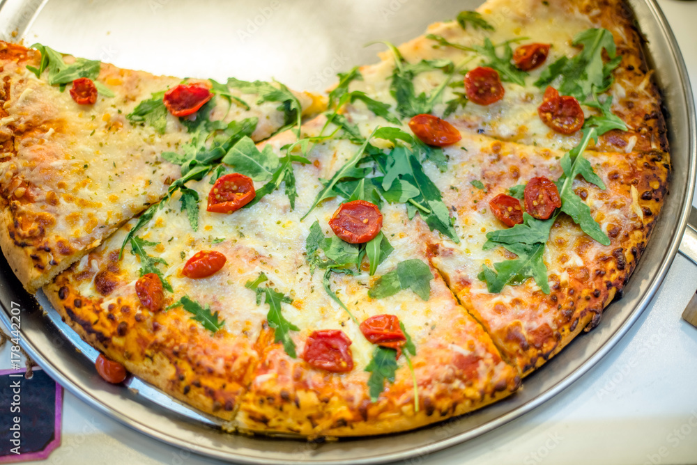 Pizza with arugula and tomatoes is on the shop window in the store Pizza with arugula and tomatoes is on the shop window in the store