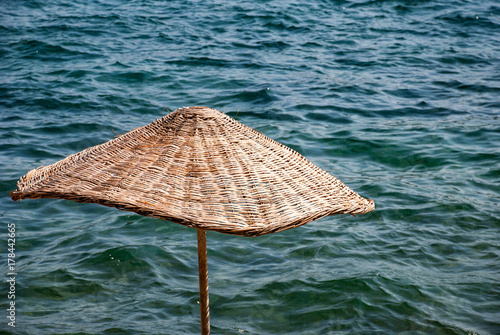 Fototapeta Naklejka Na Ścianę i Meble -  Straw umbrella on a background of water