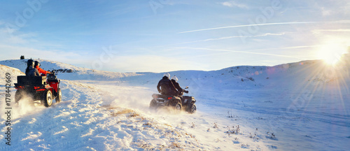 Group of female and man driving quad bike on top of the mountain at sunset