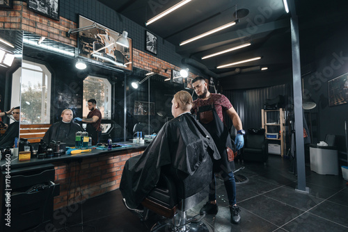 brutal hairdresser  Barber cutting in barbershop. Hairdresser at work