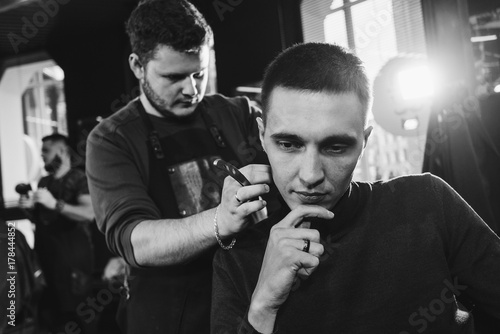 shave neck in barbershop/ Barber cutting in barbershop. Shaves the man's neck with blade. Black and white photography