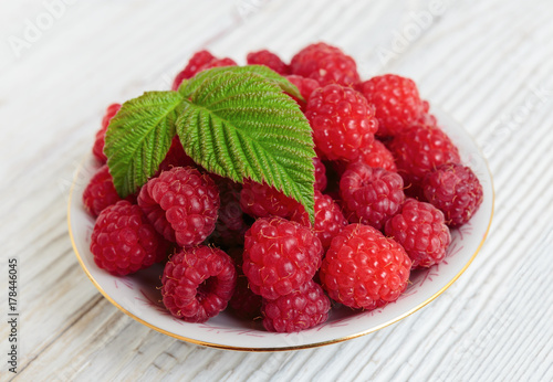 Raspberries in a bowl on a wooden white table