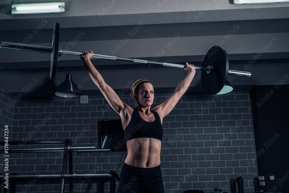 Athletic woman lifting a weight training at the gym. CrossFit Athletic woman lifting a weight training at the gym. CrossFit