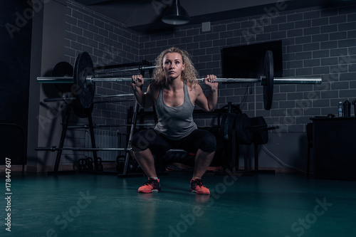 Powerful woman athlete doing squats with heavy weights. cross-training