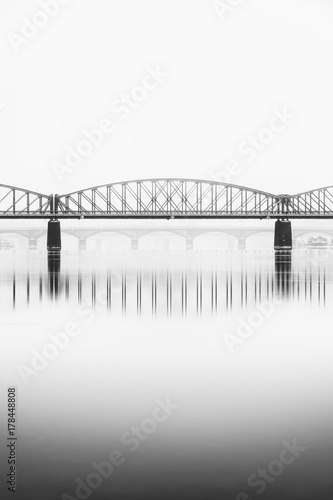 Foggy winter mood at Vltava river. Reflection of bridges in water. Black and white atmosphere, Prague, Czech republic
