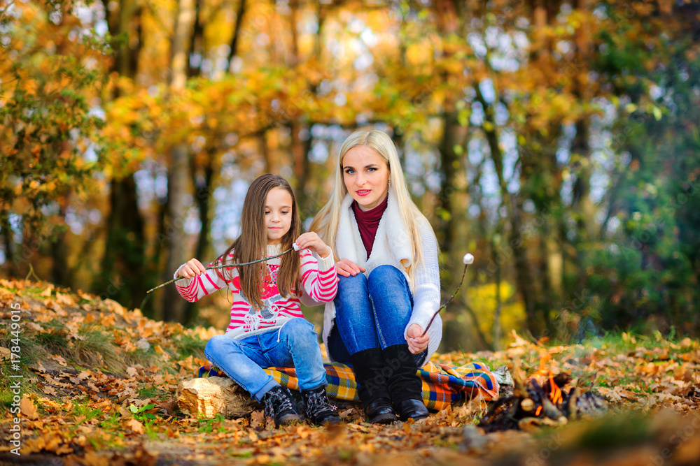 happy family outdoors in a beautiful park, fry marshmallows at the stake. happy family outdoors in a beautiful park, fry marshmallows at the stake.