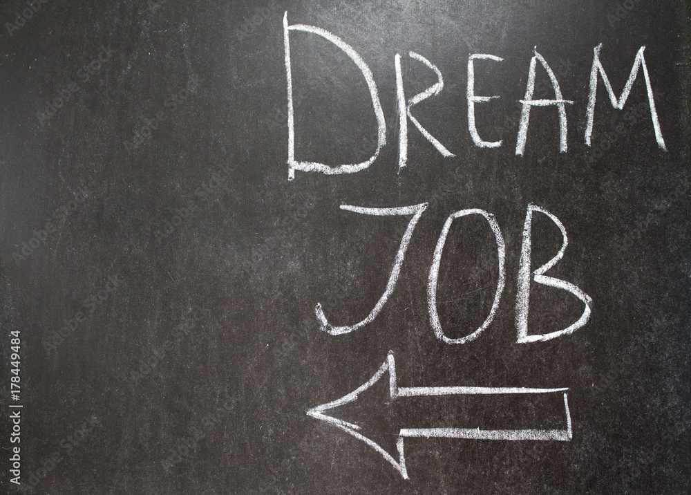 DREAM JOB message and left arrow sign hand written on the blackboard with white chalk. Copy space for text . Banner for job search. DREAM JOB message and left arrow sign hand written on the blackboard with white chalk. Copy space for text . Banner for job search.