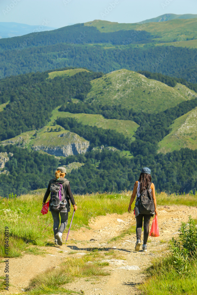 Women hiker walking down the mountain road. Women walk on a macadam road