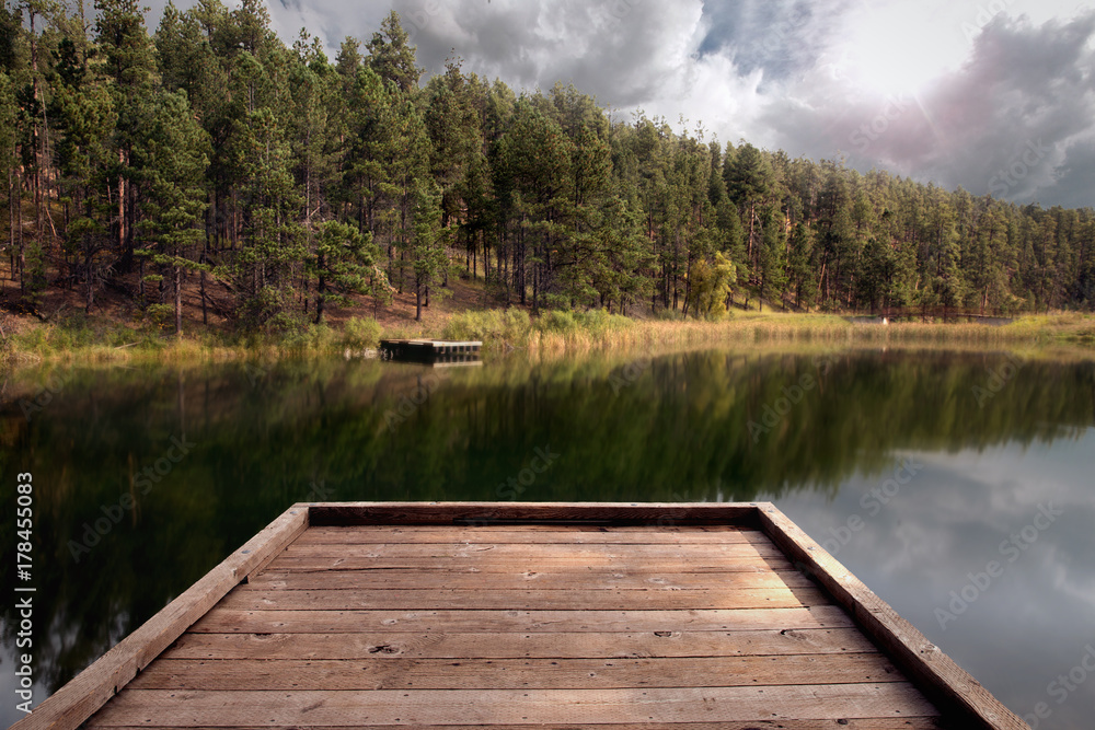Beautiful peaceful dock on calm serene fishing and swimming lake with forest in tranquil park Beautiful peaceful dock on calm serene fishing and swimming lake with forest in tranquil park