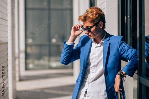 Smartly dressed businessman, smiling while stand near wall photo