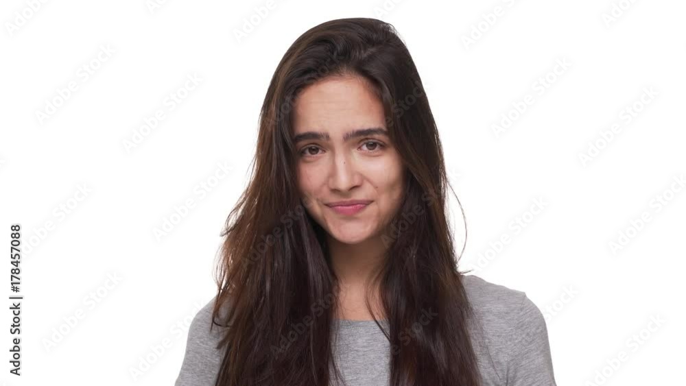 portrait of shy cute female model with long dark hair smiling at camera looking down hesitating feeling embarrassed over white background closeup. Concept of emotions portrait of shy cute female model with long dark hair smiling at camera looking down hesitating feeling embarrassed over white background closeup. Concept of emotions