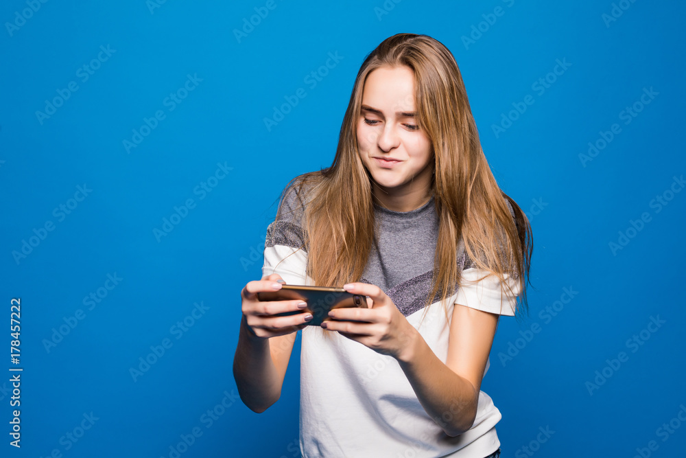 Woman play game on phone on blue background Woman play game on phone on blue background