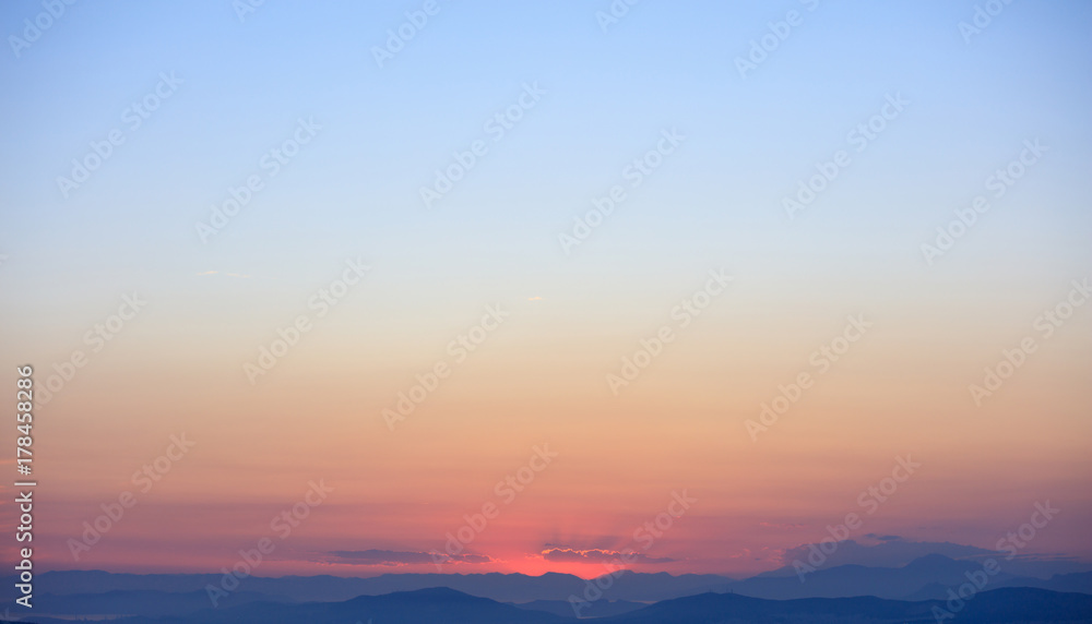 Beautiful sunset on sky over mountains background.