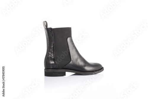 Close up of a women's black patent leather chelsea boots on white background with reflection. Fashion advertising shoes photos.