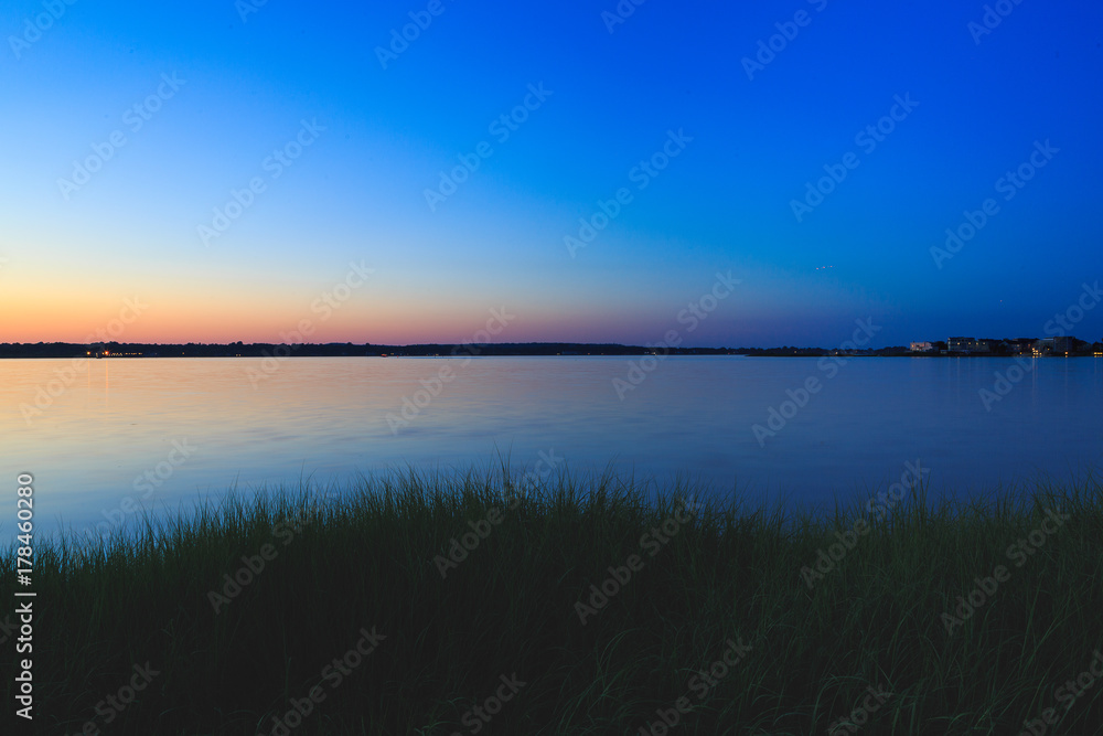 Dock, boat and marshes at sunset and blue hour off New Jersey inlet.