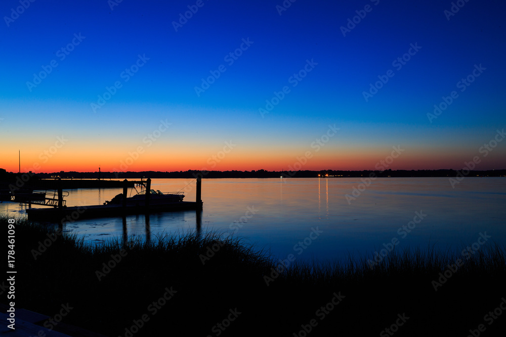 Dock, boat and marshes at sunset and blue hour off New Jersey inlet.