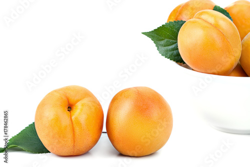 ripe juicy yellow apricots with leaves on a white table