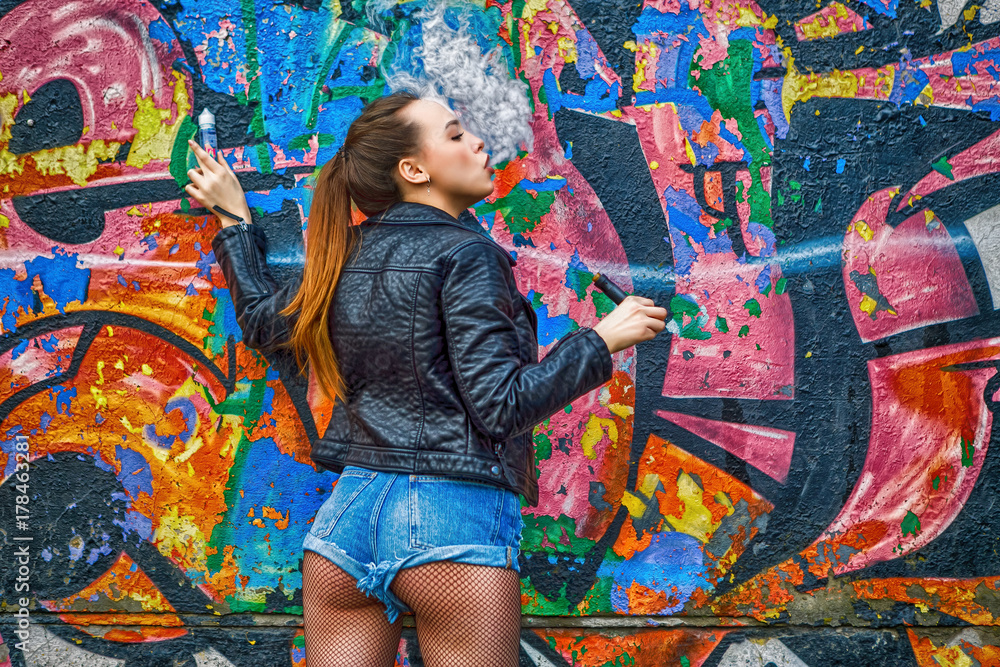Fototapeta premium Brunette girl is vaping outdoor summer lifestyle