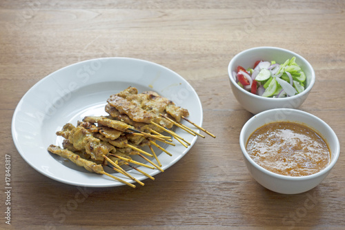 Set of pork satay in white dish on wooden table