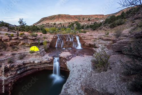 Glowing tent near rocky waterfall in Southern Utah