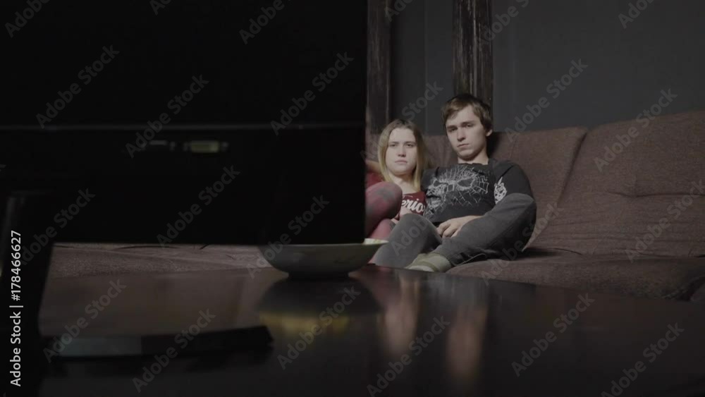 Serious young couple laughed, looking at the television. Serious young couple laughed, looking at the television.