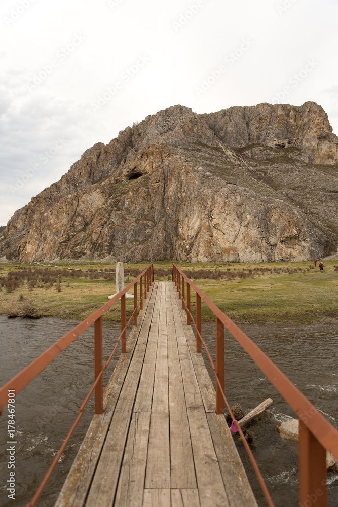 Fototapeta premium The very old hanging footbridge across a small river.