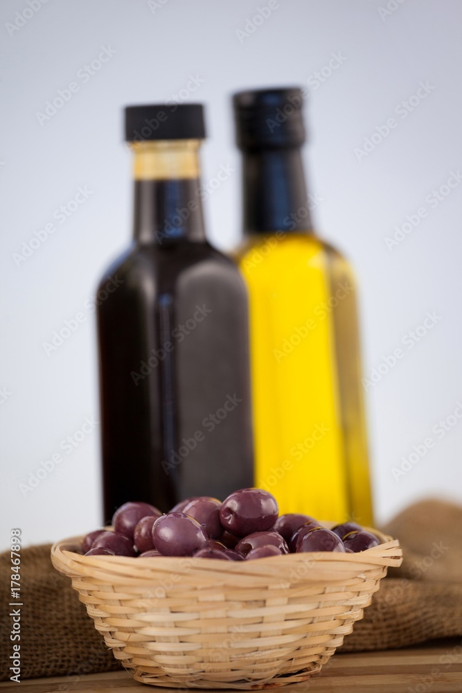 Close up of olives in wicker basket by oil bottles
