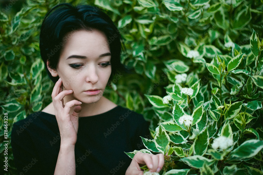 young woman with beautiful feet dressed in black dress, against a backdrop of urban landscapes bush. Street fashion. young woman with beautiful feet dressed in black dress, against a backdrop of urban landscapes bush. Street fashion.
