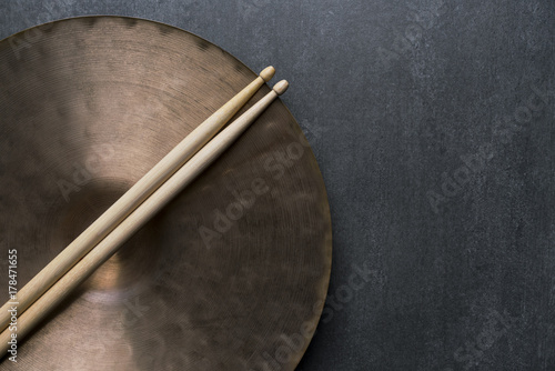 Drum stick and crash cymbal on black table background, top view, music concept